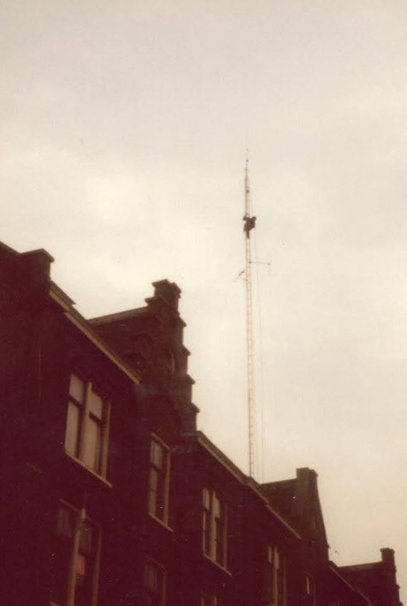 Silhouet van een antennemast op een dak tegen een bewolkte lucht